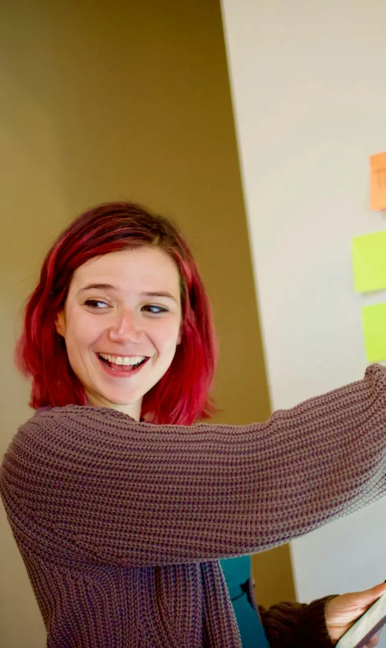 woman in gray sweater holding white and yellow sticky notes